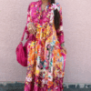 Solene viskosklänning i cerise med abstrakt print, lång modell i viskos med kort ärm och vackert fall, fotad framifrån på modell i sommarmiljö.